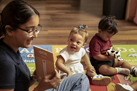 Caregiver reading to infants to promote early reading skills daycare Bulverde